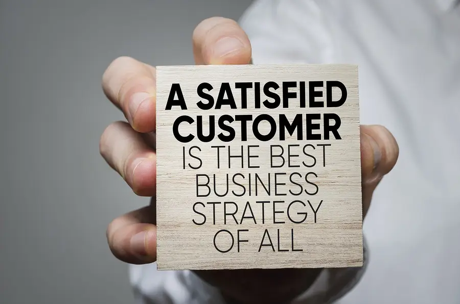 A closeup of a sign that reads "a satisfied customer is the best business strategy of all"