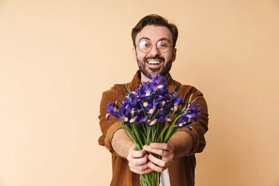 A man holding out a bouquet of flowers