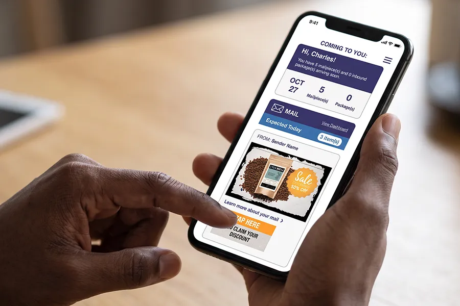 A closeup of a man's hands holding a phone showing USPS Informed Delivery